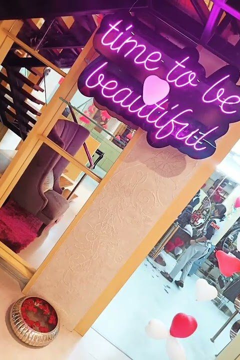 Pink neon sign reading 'time to be beautiful' inside the studio